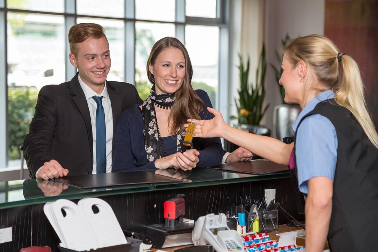 Hotel receptionist handing over key to customers
